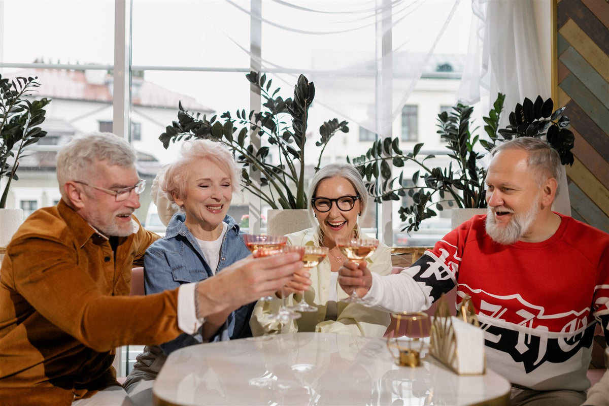 Four older friends laughing around a dining table