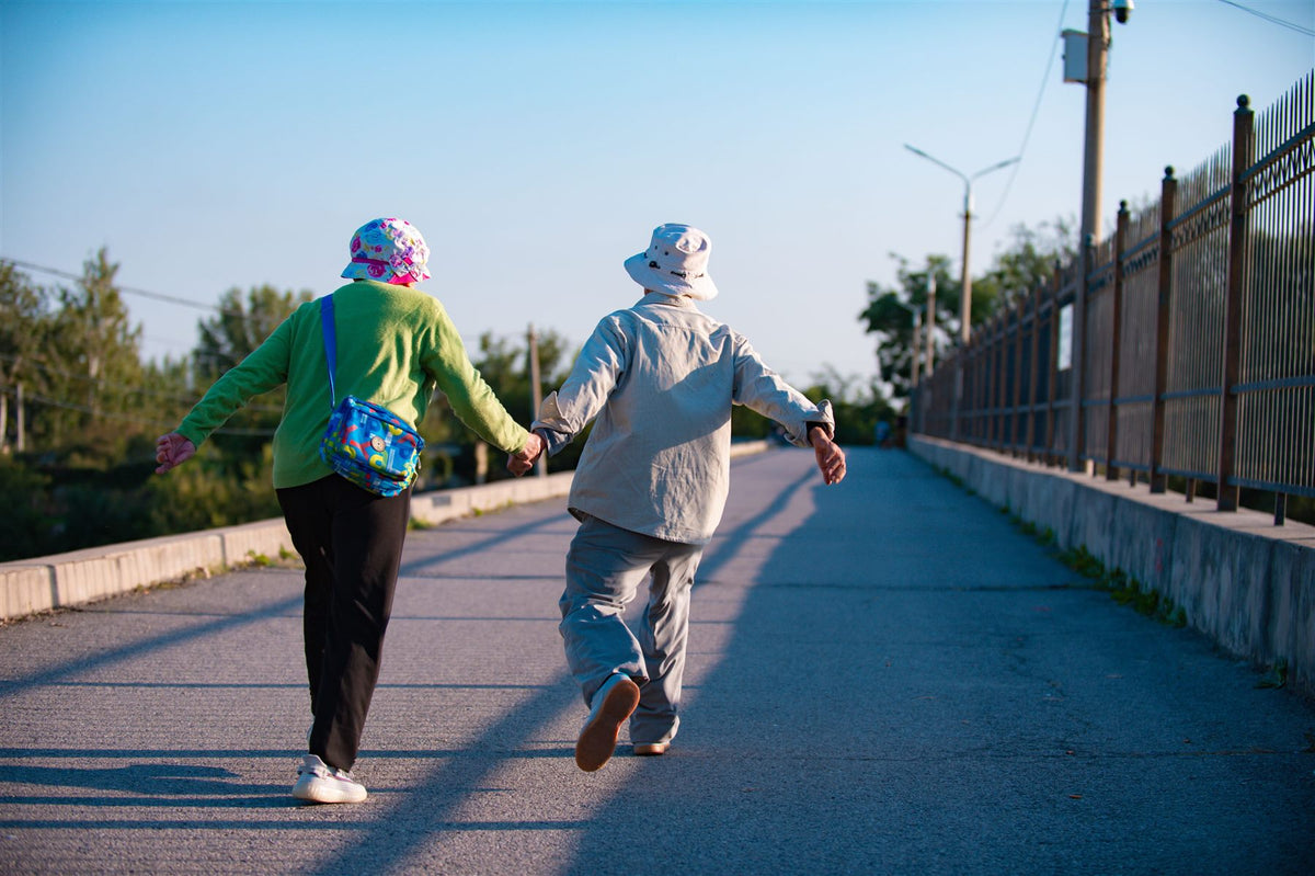 Older couple walking together along a sunny path